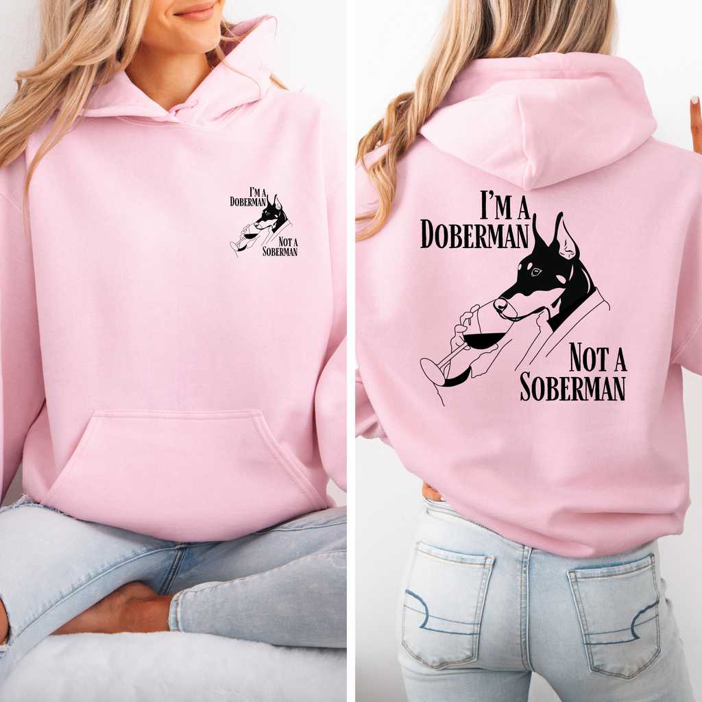 Rosafarbener Hoodie mit Dobermann-Illustration und Schriftzug „I’m a Doberman, Not a Soberman“, kleiner Print vorne, großer Print hinten.
