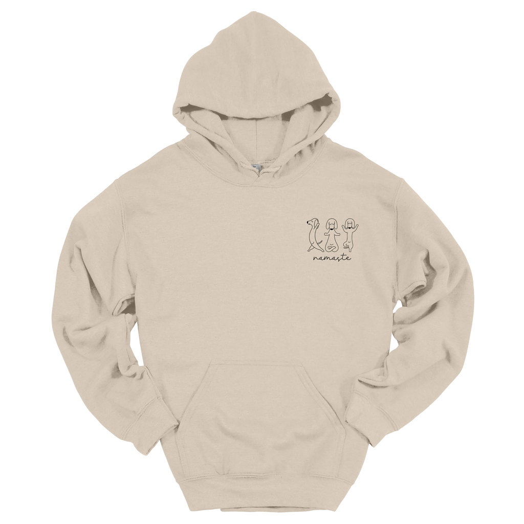 Beiger Hoodie mit kleinem Frontprint „Namaste“ und drei yoga-sitzenden Hunde-Illustrationen; Produktfoto vor weißem Hintergrund.