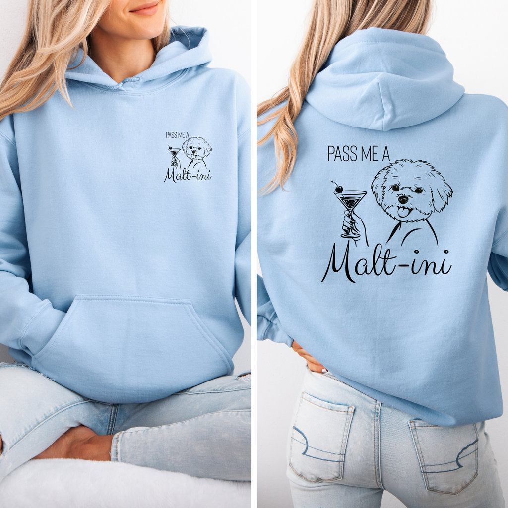 Hellblauer Hoodie mit kleinem Malteser-Frontprint und großem Rückenmotiv „Pass me a Malt-ini“, getragen von einer Frau im Sitzen.