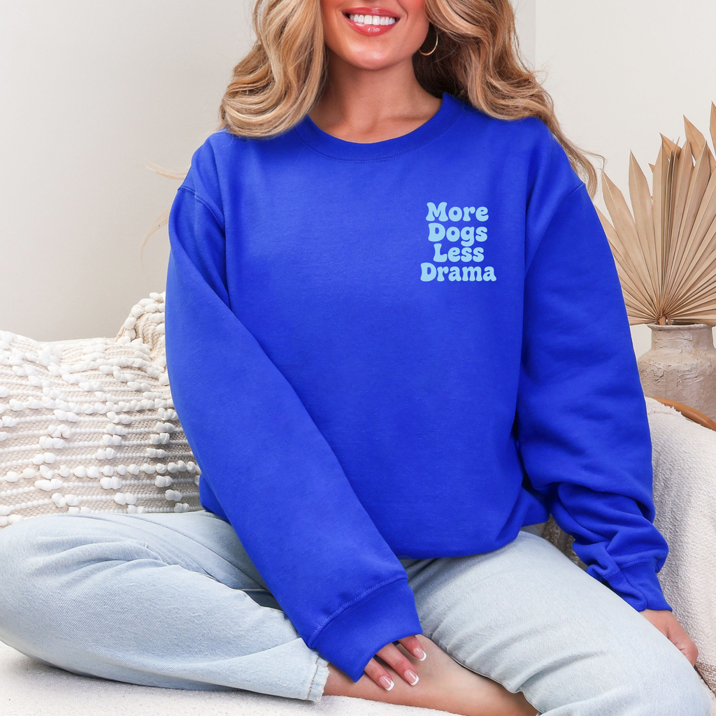 Royalblauer Sweater mit hellem Schriftzug „More Dogs, Less Drama“ auf der Brust, getragen von einer Frau.