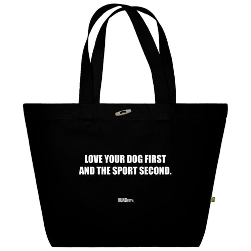 Schwarze Stofftasche mit weißem Aufdruck ‚Love your dog first and the sport second‘ von HUNDert %